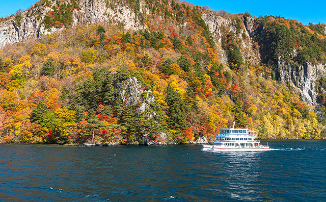 秋の十和田湖と遊覧船のイメージ